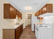 Thumbnail 6 of 15 - A kitchen with white appliances and wooden cabinets.