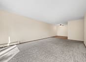 Thumbnail 11 of 15 - A large empty room with a carpeted floor and white walls.