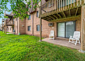 Thumbnail 2 of 15 - A balcony with two chairs and a table is on the right side of a brick building.