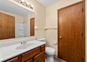 Thumbnail 15 of 15 - A bathroom with a toilet, sink, and mirror.