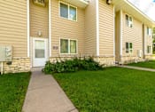 Thumbnail 2 of 15 - A building with a brown siding and a white door with windows on the side.