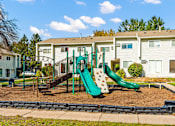 Thumbnail 13 of 14 - A playground with a green slide and a brown swing set.