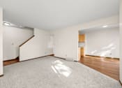 Thumbnail 7 of 14 - A large, empty room with a carpeted floor and a staircase.