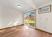 Thumbnail 5 of 14 - A room with a wooden floor and a window showing an outdoor view.
