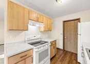 Thumbnail 1 of 14 - A kitchen with white appliances and wooden cabinets.