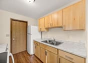 Thumbnail 2 of 14 - A kitchen with wooden cabinets and a white fridge.