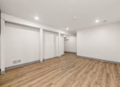Thumbnail 10 of 14 - A room with wooden floors and white walls.