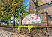 Thumbnail 10 of 11 - A sign for Henry Hill Apartments is displayed in front of a brick building.