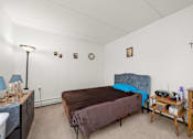 Thumbnail 7 of 11 - A bedroom with a bed, nightstand, and a lamp.