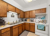 Thumbnail 3 of 11 - A kitchen with wooden cabinets and white appliances.