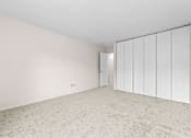 Thumbnail 11 of 23 - A room with white walls and carpeted floor with a white wardrobe.