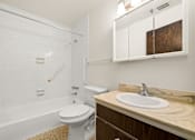 Thumbnail 13 of 18 - A white toilet sits under a white tiled shower in a small bathroom.