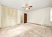 Thumbnail 8 of 18 - A room with a ceiling fan and carpeted floor.