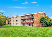 Thumbnail 18 of 18 - A red brick apartment building with a green lawn in front.
