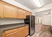 Thumbnail 1 of 18 - A kitchen with wooden cabinets and a black refrigerator.