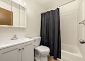 Thumbnail 9 of 15 - A white bathroom with a toilet, sink, and shower.