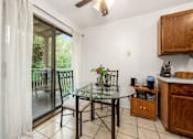 Thumbnail 4 of 15 - A kitchen with a table and chairs by a sliding glass door.