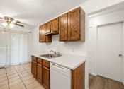 Thumbnail 2 of 15 - A kitchen with white countertops and wooden cabinets.