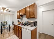 Thumbnail 6 of 15 - A kitchen with wooden cabinets and a white dishwasher.