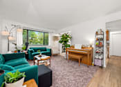 Thumbnail 1 of 15 - A living room with a green couch and a wooden desk.