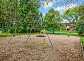 Thumbnail 14 of 15 - A playground with a swing set and a slide.