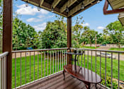 Thumbnail 7 of 15 - A wooden table is on a porch with a white railing.