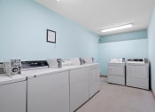 Thumbnail 21 of 22 - a laundry room with washes and dryers and a blue wall and white appliances