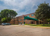 Thumbnail 3 of 14 - a large brick building with a green canopy in front of it