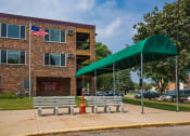 Thumbnail 1 of 14 - a building with two benches and a green canopy in front of it