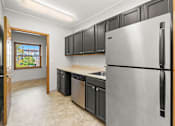 Thumbnail 6 of 23 - A kitchen with a refrigerator, sink, and cabinets.