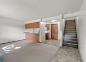 Thumbnail 12 of 21 - an empty living room with a staircase and a kitchen in the background