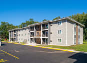 Thumbnail 9 of 27 - an apartment building with gray siding and a parking lot