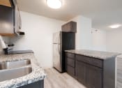 Thumbnail 13 of 27 - an empty kitchen with granite counter tops and a stainless steel refrigerator