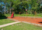 Thumbnail 2 of 27 - a swing set in a park with trees