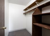 Thumbnail 17 of 22 - a walk in closet with a wooden closet door and a white wall with a shelf