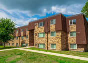 Thumbnail 6 of 22 - a brick apartment building with green grass and a sidewalk
