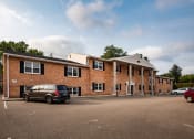Thumbnail 2 of 12 - a large brick building with a car parked in a parking lot