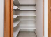 Thumbnail 12 of 21 - a walk in closet with white shelves and a door