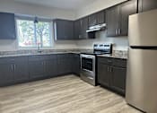Thumbnail 1 of 10 - A kitchen with black cabinets and a stainless steel refrigerator.