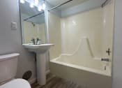 Thumbnail 4 of 10 - A white bathroom with a toilet, sink, and bathtub.