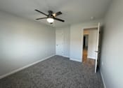 Thumbnail 6 of 10 - A room with a ceiling fan and carpeted floor.