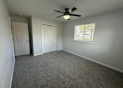 Thumbnail 8 of 10 - A room with a ceiling fan and two doors.