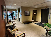 Thumbnail 20 of 20 - A waiting room with a bench, chairs, and a painting on the wall.