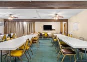 Thumbnail 21 of 23 - a conference room with long tables and chairs and a tv