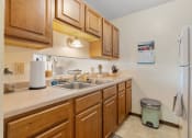 Thumbnail 8 of 23 - a kitchen with a sink and refrigerator and wooden cabinets