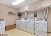 Thumbnail 23 of 23 - a laundry room with a row of washes and dryers in it
