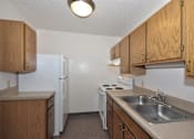Thumbnail 3 of 7 - A small kitchen with a white refrigerator and a white stove.