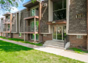 Thumbnail 4 of 28 - an exterior view of a brick apartment building with a sidewalk and grass