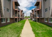 Thumbnail 2 of 28 - a walkway between two rows of buildings with grass on both sides