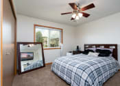 Thumbnail 9 of 12 - a bedroom with a bed and a mirror and a ceiling fan